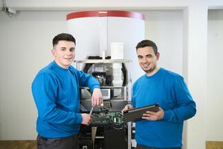 Zwei junge Anlagen-Mechaniker stehen vor einer Solvis-Heizungsanlage